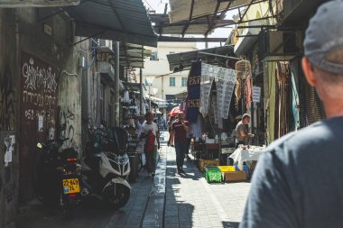 Tel Aviv / İsrail-10 / 10 / 18: Sıcak, güneşli bir yaz gününde, Eski Jaffa şehrindeki Jaffa Bit Pazarı 'nın dar bir caddesinde yürüyen insanlar