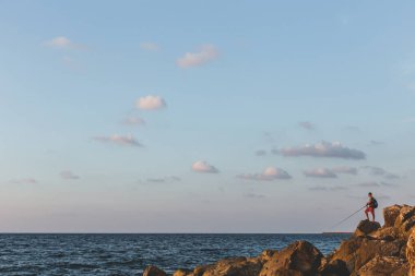 Tel Aviv / İsrail-10 / 10 / 18: günbatımında Tel Aviv Marina yakınlarında bir balıkçı oltasıyla balık tutan adam