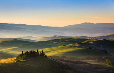 Gün doğumunda, Tuscany, İtalya 'daki sarp tepeler ve yeşil tarlalar
