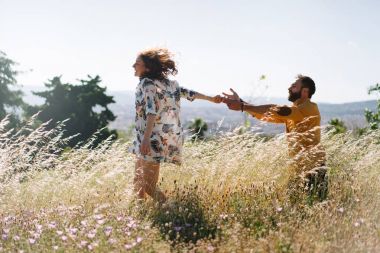 Büyüleyici romantik çift sıcak güneşli yaz günü çayır ortasında çalışırken keyif alıyor. Bir erkek ve bir kadın aşık gün açık havada harcama vardır. Yeni evli genç bir çift portresi.