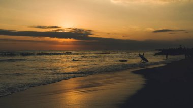 Gece olduğunda siluetleri sörfçü, renkli deniz manzarası. Tropikal kum plajı güzel günbatımında. Arkadaşlar dalga yoktu ile tropikal Denizde yüzme yaz tatili harcama.
