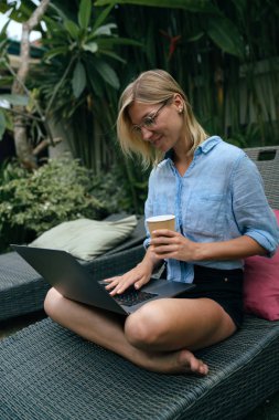 Başarılı seyahat blogger sabah kahvesi yaz tatili bir taşınabilir bilgisayarda çalışırken sahiptir. Sarışın kadın havuzun yorgunluk bir dizüstü bilgisayarın görüntü e-postaları okuma.