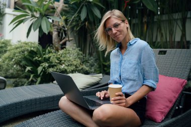 Profesyonel tasarımcı erkek sabah kahvesi yaz tatili bir taşınabilir bilgisayarda çalışırken sahiptir. Kadın yenilikçi havuzun yorgunluk bir dizüstü bilgisayarın görüntü e-postaları okuma.