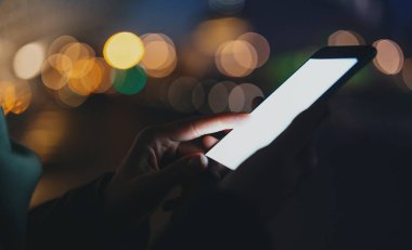 Kadın holding modern smartphone elinde closeup görünümü. Boş kopya alanı sayfa metin mesajınız için kaydırma veya reklam içeriği kız. Yatay, bulanık arka plan, bokeh etkileri.