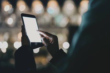 Kadın holding modern smartphone elinde closeup görünümü. Metin iletiniz için boş kopya alanı ekranda parmakları işaret veya reklam içeriği kız. Yatay, bulanık arka plan, bokeh etkileri.