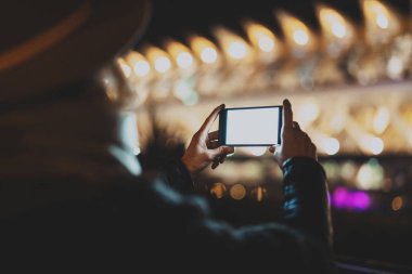 Tatlı bir kadın tarafından bir cep telefonu metin iletiniz için bir boş kopya alanı ekran ile fotoğraf çekme veya reklam içeriği arkasından görüntüleyin. Yatay, bulanık arka plan, bokeh etkileri.