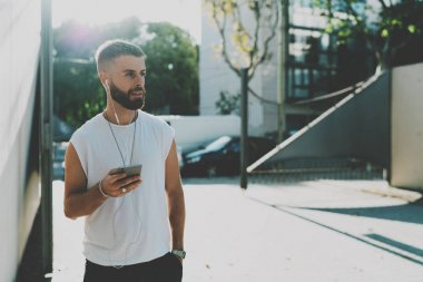 Yetenekli tasarımcı yaz güneşli bir günde sokakta yürürken bir cep telefonu istemcilerinden gelen e-postaları okuma. Hipster sakallı adam açık havada dinlenme sırasında bir smartphone cep telefonu ile müzik dinlemek.