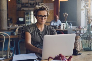 Taşınabilir bir bilgisayar ile bir kafede oturan bir ortak wi-fi için bağlıyken genç beyaz kadın online bankacılık. Girişimci kadın bir kafede Kahvaltı yaparken bir dizüstü bilgisayarda çalışıyor.