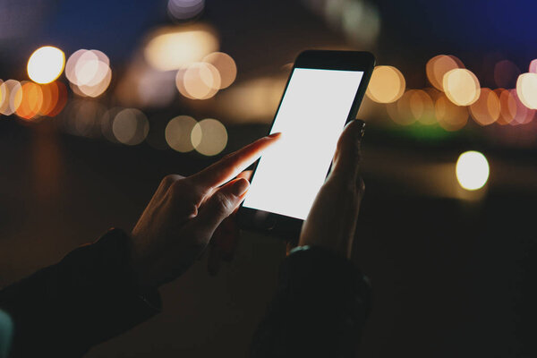 Cropped image of woman's hands holding mobile phone with blank copy space screen for your text message or advertising content, femalereading ebook on smartphone while relaxing outdoors.