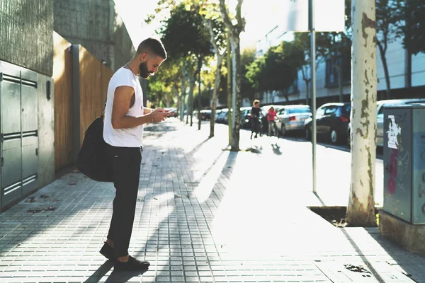 ひげを生やした流行に敏感な人は街角に立っている間携帯電話でオンライン チャット スタイリッシュな服を着た 野外を歩いている時にスマート フォンでメールを読んで起業家男性 — ストック写真