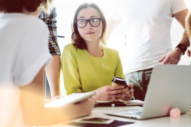 Modern başlangıç genç satış uzmanları iş stratejisi gelecek yıl için modern ve aydınlık ofiste görüşüyorlar. Öğrenciler elektronik cihazlar ile toplantı sırasında oturuyorsun.