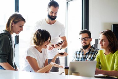 Grup iş öğle süre içinde modern bir taşınabilir bilgisayarda son pazarlama haberleri okuyor. Genç yöneticileri iş fikirleri proje yeni dijital başlatmak için görüşüyorlar.