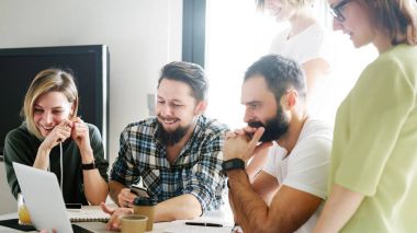 Grup genç girişimcilerin yeni iş fikirleri ortakları ile çevrimiçi toplantı sırasında tartışıyor. Takım lideri taşınabilir bir bilgisayar kullanarak tasarımcılar ekibi yeni bir proje sunuluyor. 