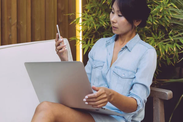 年轻的女企业家在一个现代 Coworking 的空间工作 手机和便携式电脑连接到 国际亚裔学生正在用笔记本电脑在线学习 — 图库照片