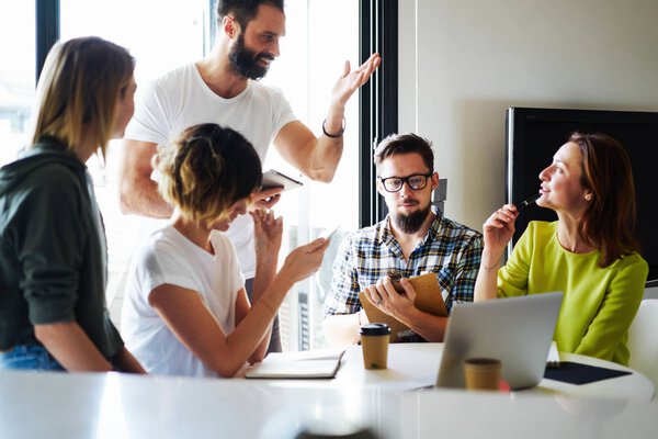 Young and successful entrepreneurs are working on the marketing project at the modern coworking space. Group of colleagues are generating new business ideas for new start up project.