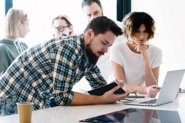 Satış Yöneticileri grup serbest zaman sırasında modern bir taşınabilir bilgisayarda son dijital haber okuyor. Genç Girişimciler Yeni iş fikirleri proje yeni başlangıç için görüşüyorlar.