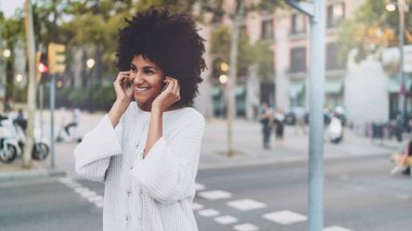 Modeli göz erkek cep telefonu ile şehir yürürken kulaklık müzik dinlemek. Açık havada rahatlatıcı bir müzik ile serbest meslek sahibi kadın indirilen ve Smartphone'da oynadı.