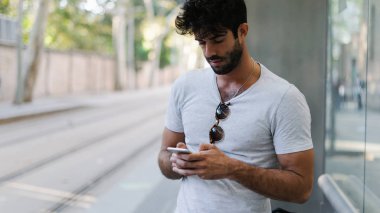 Bir hafta sonu yeni bir proje üzerinde çalışma arkadaşları iletileri okuma profesyonel web tasarımcısı. Genç adam otobüs beklerken bir cep telefonuyla taşıma uygulama üzerinde sakallı.