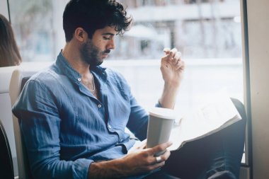 Genç Ofis Yöneticisi erkek gitmek casuak giysili bir otobüs ile kahve oturuyor ve gazete okuma. Tren ile çalışmaya devam ederken basın piyasa haberleri analiz iyi giyimli pazarlama uzmanı.