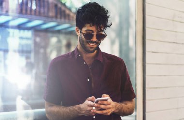 Sakallı erkek rahat outifit cep telefonuyla dururken kentsel çevre, varoluş portresi. Smartphone'da şehir yürüyüş sırasında sohbet şık elbise giymiş adam.