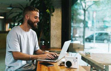 Genç fotoğrafçı teklif sonraki fotoğraf oturumu için reklam için e-posta ile almak için mutlu. Bir dizüstü bilgisayar tarafından online onun projesi için olumlu yorumlar okuma yetenekli web tasarımcısı.