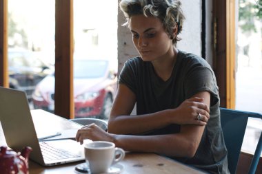 Serbest meslek, modern bir taşınabilir bilgisayarın ekranını e-postaları bir kafede otururken okuyor. Genç tasarımcı modern bir kafede Kahvaltı yaparken yeni proje üzerinde çalışıyor.
