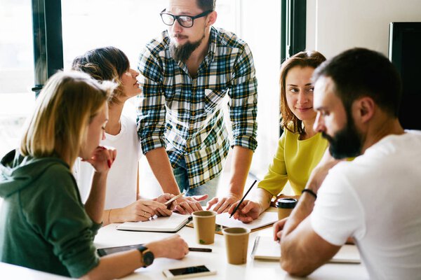 Group of digital marketing specialists is working on the new project concept by writing down all the ideas. Young managers are brainstorming during meeting on the new marketing promotion project.