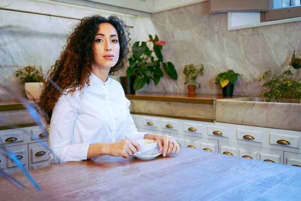 beautiful curly young woman with cup of coffee in a cafe 