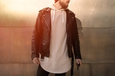 Bir metal duvar arka plan üzerinde beyaz boş sweatshirt ve deri ceket ayakta giyen genç adam