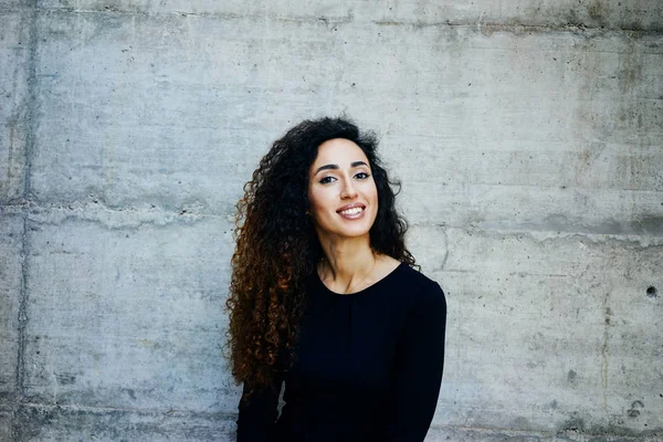 Joven Mujer Sonriente Con Pelo Rizado Largo Pie Contra Pared —  Fotos de Stock