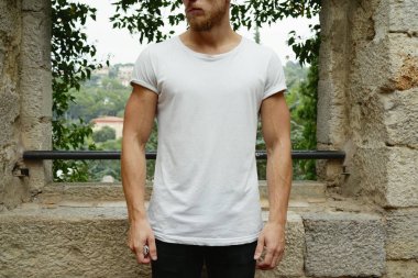 Görüntüsünü şık genç adam açık havada beyaz t-shirt giyen kırpılmış