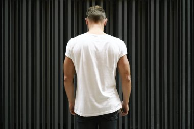 Boş beyaz t-shirt üzerine siyah duvar arka plan üzerinde kas genç adam