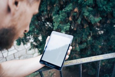 Yakışıklı genç adamın metal çit yakınındaki dijital tablet kullanarak resim kırpılmış