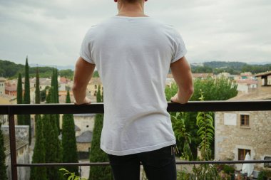 Adam beyaz t-shirt giyen bir şehir arka plan üzerinde arkadan görünüm 