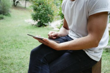 genç adam parkta otururken tablet kullanma