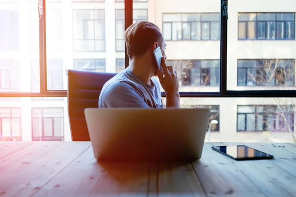 Junger Geschäftsmann Arbeitet Laptop Während Büro Mit Dem Smartphone Spricht — Stockfoto