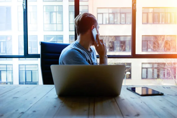 Junger Geschäftsmann Arbeitet Laptop Während Büro Mit Dem Smartphone Spricht — Stockfoto