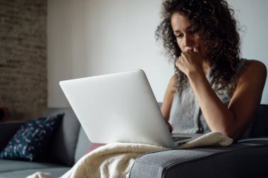 güzel genç kadın evde kanepede otururken dizüstü bilgisayar kullanarak