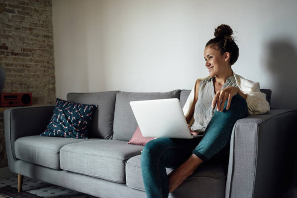 Beautiful young woman sitting with open laptop on her knees