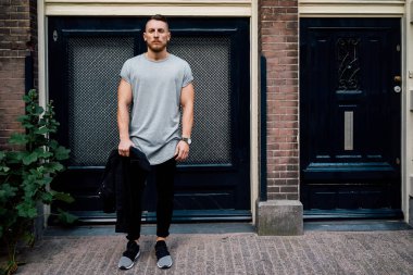 boş gri t-shirt ayakta giriş kapısı karşı bir sokakta giyen yakışıklı hipster adam 