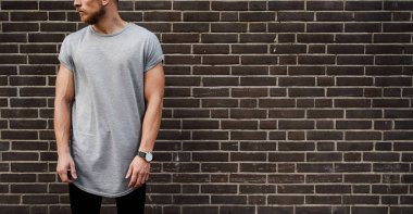 boş gri t-shirt giyen ve karanlık duvara karşı duran genç bir kaslı adam kırpılmış görüntü 