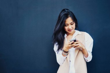 Genç Asyalı kadın siyah duvar arka plan üzerinde smartphone kullanarak Portret 