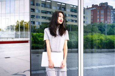 güzel Asyalı kadın modern scyscraper poz dizüstü bilgisayar ile