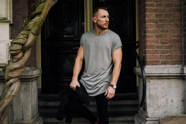 Bir boş gri t-shirt entance kapı karşı poz giyen genç kas hipster adam