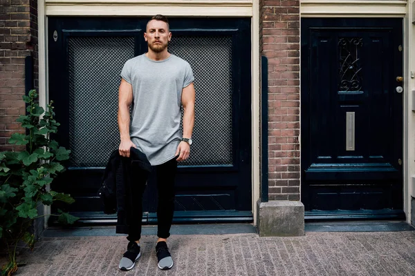 boş gri t-shirt ayakta giriş kapısı karşı bir sokakta giyen yakışıklı hipster adam 