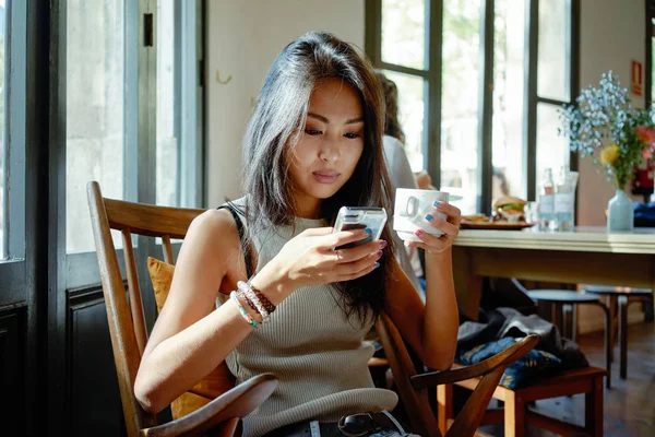 Ung Vakker Asiatisk Kvinne Som Bruker Smarttelefon Mens Hun Drikker – stockfoto