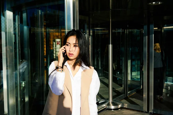 年轻迷人的亚洲妇女在商务中心外电话交谈 — 图库照片