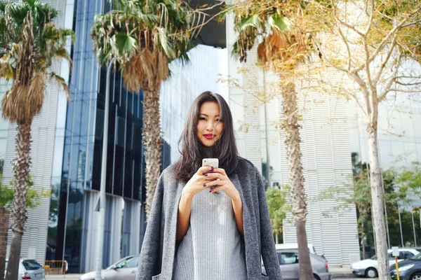 Schöne Asiatische Frau Mit Smartphone Gegen Modernen Wolkenkratzer — Stockfoto