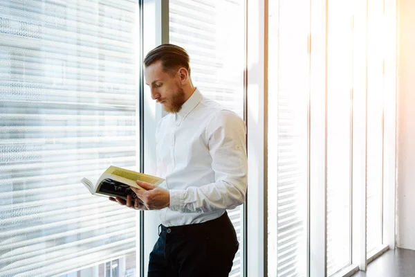 Ung Mann Leser Bok Nær Vinduet Lunsjpausen Kontoret – stockfoto