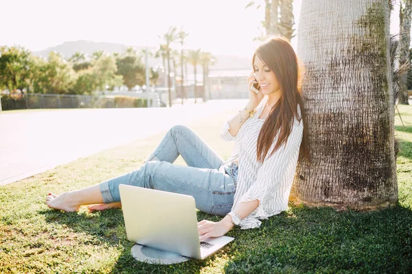 Jonge Vrouw Praten Telefoon Tijdens Het Gebruik Van Een Laptop — Stockfoto